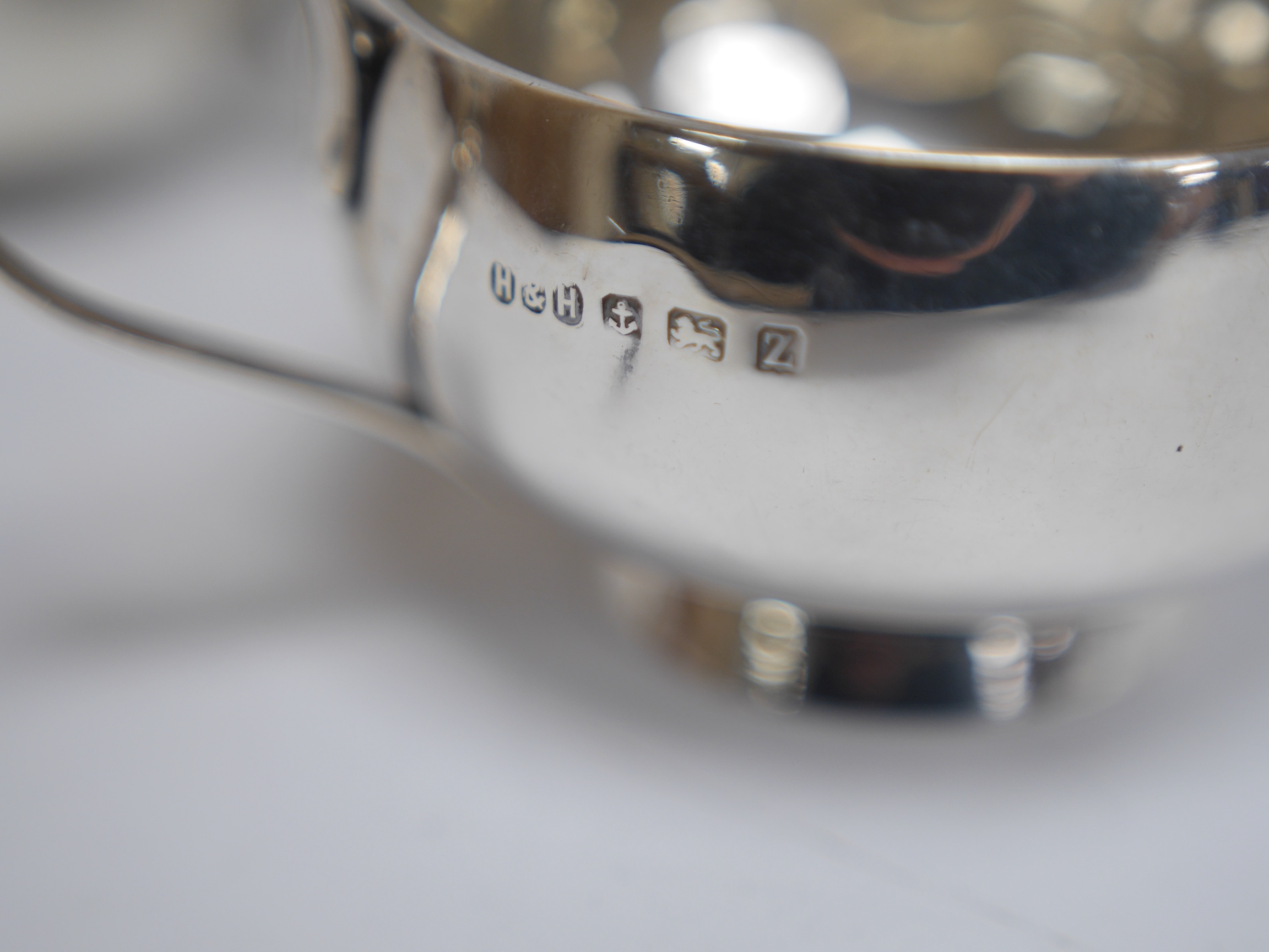 A late Victorian silver porringer, London, 1897, height 61mm, an Edwardian silver porringer, a late Victorian repousse silver sugar bowl and a George V silver cream jug by Hukin & Heath, 17.1oz. Condition - poor to fair